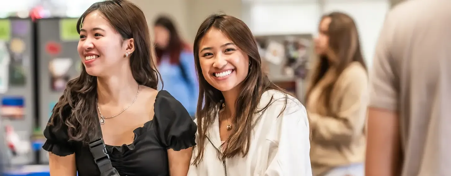 Two female students smiling at a club event